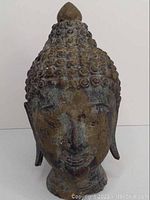 Full front view of the bronze Buddha head on a white background