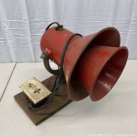 Front view of red siren and attached switch on wooden board