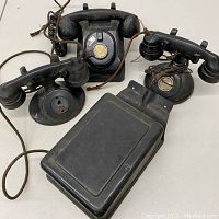 Three telephone units and a ringer box displayed on table