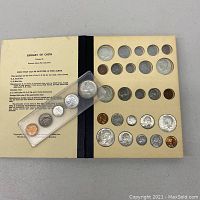 Full view of coin album titled 'Library of Coins' with slots for each coin from 1964 to 1974. Coins inserted into designated slots including Kennedy half dollars, quarters, dimes, nickels, and pennies.