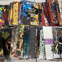 Photo showing various comic books including Batman titles, with some covers visible such as Batman: Gotham Knights and Batman: Gotham Adventures.