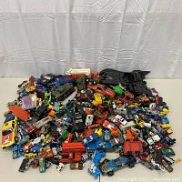 Wide view of entire lot showing pile of small diecast cars and Batmobile at rear