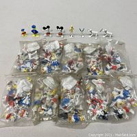 Overall view of 10 sealed plastic bags containing loose Disneykin figures with sample figures displayed on top
