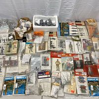 Overview of assorted unpainted lead soldier kits and loose figures on table.