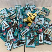 Wide view of entire lot of diecast miniature pencil sharpeners in teal boxes scattered on table