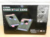 Box showing two football field themed cornhole boards and multiple bean bags with a picture of a child playing the game.