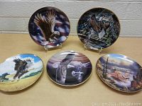 Five American Bald Eagle collector plates arranged on a table, showing different stylized eagle artwork and backgrounds.