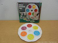 Photo showing the white serving tray with six colorful coasters placed in slots and original box in background.