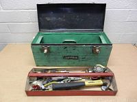 Green Craftsman metal toolbox open, showing empty interior with removable tray placed in front containing tools.