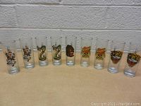 Photo of 10 Ed Hardy shot glasses in a row showing full designs
