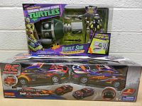 Photo showing the Ninja Turtle Turtle Sub box stacked on top of the RC racing car set in original packaging with both items.