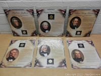 Six individual United States presidential coins displayed on patriotic photo pages, arranged upright on a table showing portraits and text.