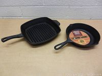 Top-down angled view of both cast iron pans showing shape and size difference, including the Lodge Logic label inside the round pan.
