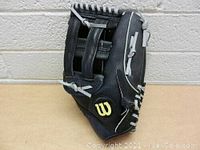 Photo showing black leather Wilson softball glove with gray laces and Wilson logo on thumb