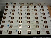 Top view showing the lot of 47 individual envelopes, each featuring a gold plated replica stamp mounted on maroon velvet backing, alongside the original postage stamp and official cancellation marks.
