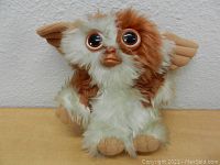 Front view of the Gizmo plush doll showing brown and white fur, large eyes, and beige features.