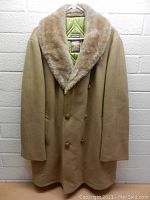 Front view of men's vintage Mighty Mac overcoat, showing tan fabric, wide plush fur collar, double-breasted button closure, and quilted green interior lining.