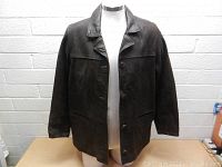 Front view of dark brown Oakwood leather jacket with button closure and collar on mannequin.