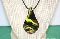 Close-up of the teardrop-shaped glass pendant showing gold/yellow and black abstract swirl design.