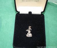 Photo showing the pendant inside original black velvet presentation box, pendant visible centered on black velvet interior.