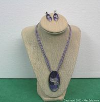 Front view of necklace and earrings displayed on bust stand showing overall appearance and length.