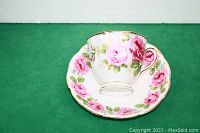 Royal Albert bone china teacup placed on matching saucer showing pink roses decoration and gold rim.