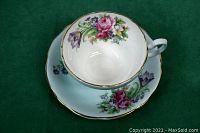Top view showing teacup inside saucer, floral pattern on baby blue background with gold trim.