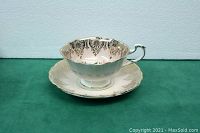 Side view of Paragon teacup on saucer, showing delicate gold pattern and scalloped edges
