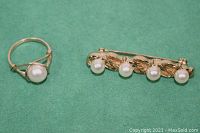 Photo showing gold-tone pearl ring and Sarah Coventry brooch with four faux pearls on green background.