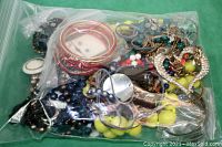 Zip lock bag filled with assorted broken jewelry pieces including beads, bangles, and chain fragments.