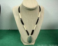 Overall view of the necklace hanging on a beige fabric display bust, showing full necklace length and bead pattern.