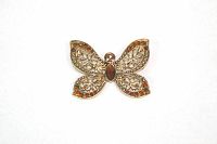 Front view of gold tone butterfly brooch showing filigree cut wings with rhinestone embellishments in amber and clear colors, plus central marquise-shaped reddish-brown rhinestone.