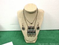 Necklace and earrings displayed on beige bust, showing overall length and pendant detail.