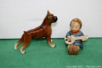 Photo showing side view of the dog figurine and young girl figurine with banjo on green background.