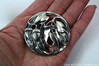 Large vintage flower brooch held in hand showing size and floral silver design