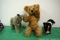 Photo showing all three stuffed animals - teddy bear standing in center, donkey on left, cow on right