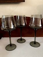 Three vintage smoked glass wine glasses displayed side by side showing full profile from front and side view capturing their shape and color.