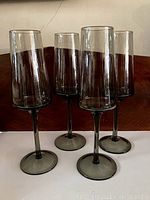 Four smoked glass Prosecco glasses displayed upright showing the full profile and smoky color.