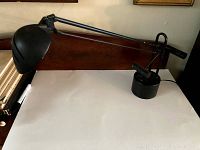 Side view of cantilever desk lamp showing the full length articulated arm and weighted base on a white surface.
