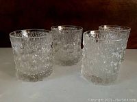 Set of four textured clear glass drinking glasses with an icicles pattern, approximately 3 inches high.