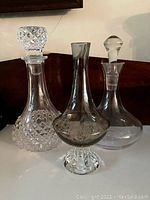 Overview of three different vintage decanters with stoppers, arranged side by side for condition and style display.
