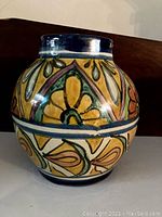Front and side view of the hand-painted floral and geometric wall pocket with blue rim and multicolor patterns.