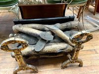 Front view of the firelog heater showing intertwined realistic faux wood logs on a metal grate with curved brass-colored feet.