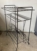 Side angled view of the vintage wire record and book rack showing multiple tiers and vintage patina.