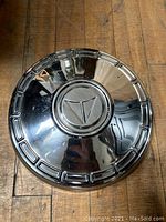 Photo of vintage 1960s AMC hubcap showing chrome finish and AMC emblem