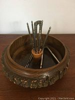 Front view of vintage nutcracker set shows wooden bowl with bark edge and six metal nutcracker tools held in center holder.