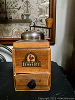 Front and side views of the vintage wooden coffee grinder showing the brand label 'Lehnhartz' with a rooster logo and a small black knob drawer.