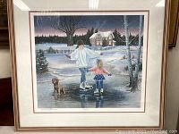 Framed print showing two girls ice skating on a frozen pond with a dog and house in the background, winter setting.