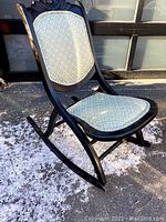 Front view of vintage folding rocking chair showing the dark wood frame and light blue upholstered seat and backrest.