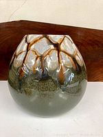 Side view of the pottery dish highlighting the textured drip glaze pattern in olive green, beige, and brown.